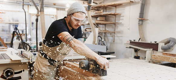 Man with safety goggles cutting wood